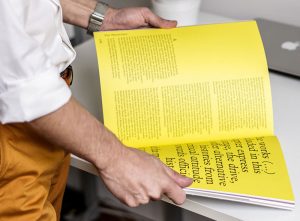 a mans hands holding a yellow book